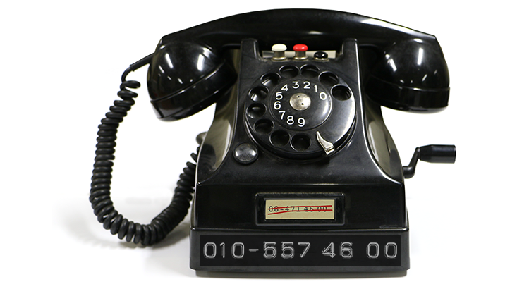 Gammal bakelittelefon med en dymotejp som visar det nya växeltelefonnumret 010-557 46 00
