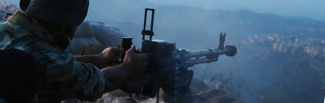 Soldat i närbild bakifrån som siktar med sitt vapen ut över ett disigt landskap