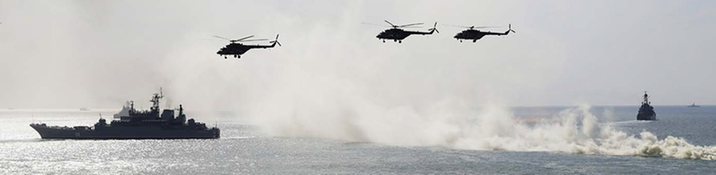 Militär aktivitet med helikoptrar i luften och båtar till havs